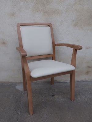 a wooden chair with a white upholstered seat next to a wall