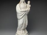 une statue blanche représentant une femme tenant un enfant dans ses bras