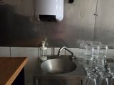 a stainless steel sink in a small kitchen with a lot of glasses on the counter