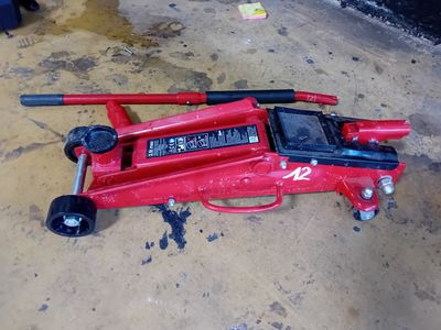 un cric rouge posé par terre dans un garage