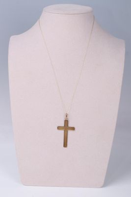 a gold cross necklace on a mannequin neck with a white background