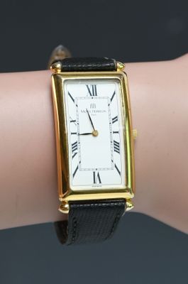 a gold and black wrist watch on a woman ' s arm