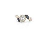 a close up of a diamond and sapphire ring on a white background