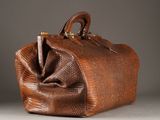 an old brown purse with a pen in it sitting on a table