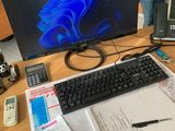 un bureau sur lequel se trouvent un ordinateur, un clavier, un téléphone et d'autres fournitures de bureau