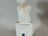 a figurine of a boy sitting on top of a toilet