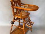 an old wooden high chair with a tray on top of it
