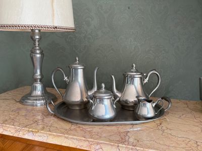 un plateau avec des théières en argent et une lampe posés sur une table