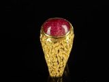 a close up of a gold ring with a red stone in it