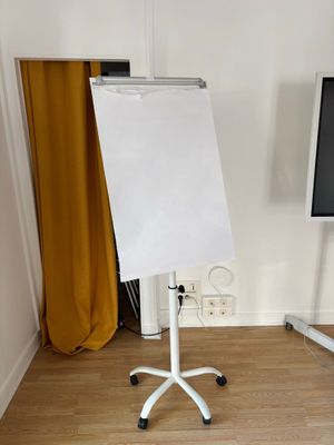 un tableau blanc posé sur un support devant un téléviseur à écran plat