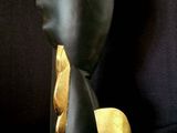 a black and gold sculpture of a woman ' s head on a black background