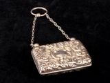 an antique silver purse on a chain on a black background