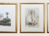 trois tableaux encadrés représentant des ruines antiques et des palmiers, accrochés au mur