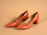 une paire d'escarpins orange à talons festonnés sur une base beige