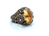 an image of a ring with a yellow stone surrounded by brown diamonds