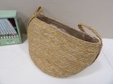 a wicker basket with a handle on a table next to a green box