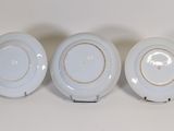 three white plates with gold rims are sitting on a table