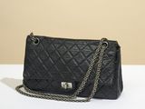 a black quilted purse with a chain strap on a white table