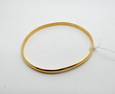 gros plan d'un bracelet en or sur une surface blanche