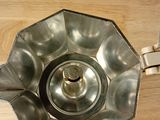 a metal bowl on a wooden table with a knife in it
