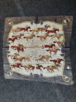 un gros plan sur un foulard carré orné de chevaux et de jockeys