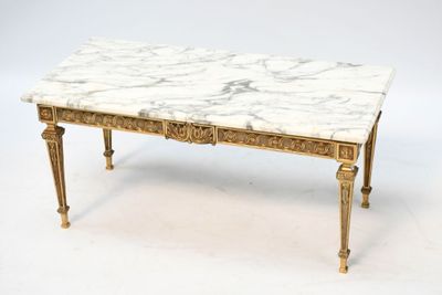 une table basse au plateau en marbre blanc, avec des pieds dorés