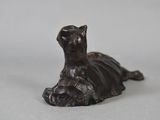 bronze statue of a cat laying down on a white surface