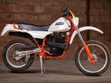 a white and orange dirt bike parked in front of a brick wall