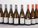 six bottles of wine are lined up in a row on a white surface
