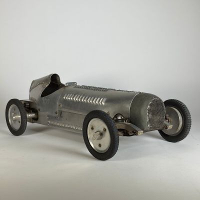 une maquette en métal d'une voiture de course posée sur une surface blanche