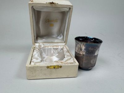 une tasse en argent posée à côté d'une tasse en argent dans une boîte