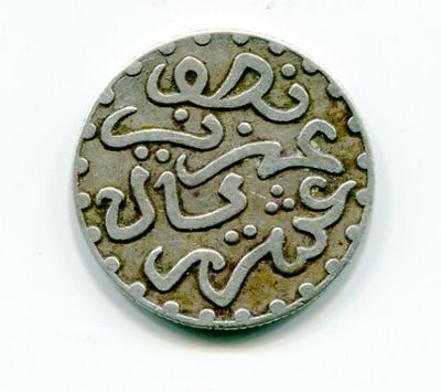 une vieille pièce de monnaie portant une inscription en arabe, posée sur une surface blanche