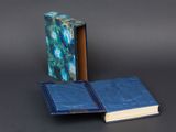 an open book sitting on top of a table next to a blue book
