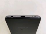 a close up of the back of a black samsung phone on a white surface