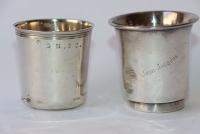une paire de tasses en métal argenté sur lesquelles sont gravés des noms