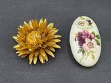 two brooches with flowers on them on a table