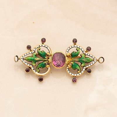 a close up of a brooch with a pink stone