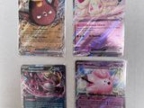 four different pokemon cards sitting on top of a white surface