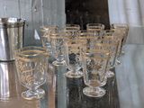 bottles and glasses are lined up on a table next to a silver vase