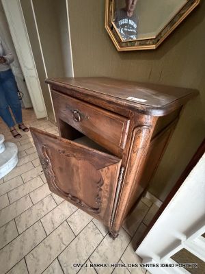 a woman taking a picture of a dresser in a bathroom