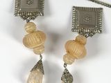 two necklaces and a pair of earrings sitting on a table