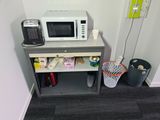 a microwave sitting on top of a table next to a trash can