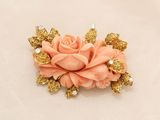 a pink flower with gold leaves and pearls on it