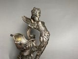 a silver statue of a woman with a bird on a pedestal