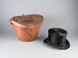 un chapeau noir et un seau marron posés sur une table blanche
