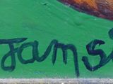 graffiti on a green wall with a picture of a man riding a skateboard