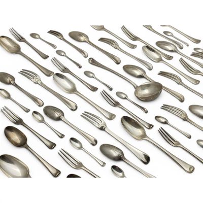 de nombreuses cuillères et fourchettes disposées ensemble sur une surface blanche