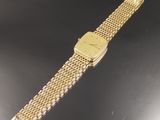une image représentant une montre-bracelet en or posée sur une surface noire
