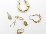 un assortiment de boucles d'oreilles et de bagues en or sur un fond blanc