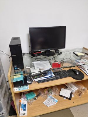 a computer desk with a monitor, keyboard, mouse, and other items on it